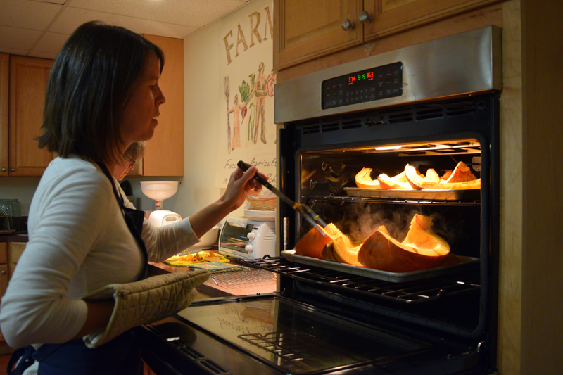 Kate McCarty, food preservation professional with the University of Maine Cooperative Extention, checks on pumpkins in the oven. (Jessica Clifford photo)