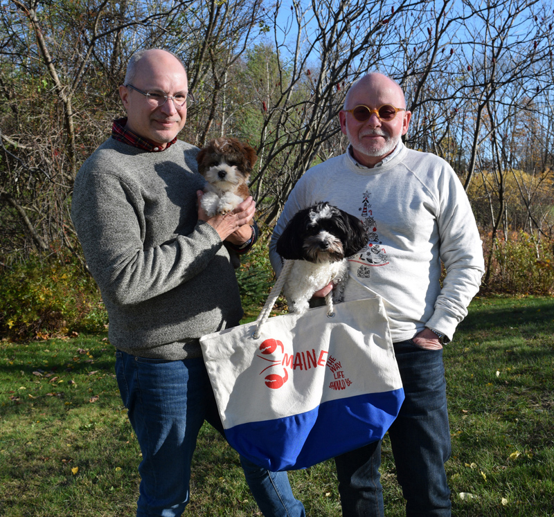 From left: Don Bostick holds Peter and his husband, Danny Cain, holds Milly. Cain is wearing a sweatshirt from their Citizen Maine holiday collection and holding a tote bag from the lobster collection. (Jessica Clifford photo)