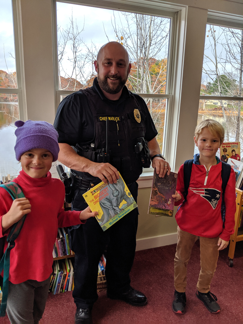 Damariscotta Police Chief Jason Warlick gives books from Skidompha Secondhand Book Shop to Josie and Lucas Branson.