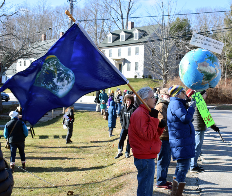 People hold flags, a globe, and signs during a climate change rally at Veterans Memorial Park in Newcastle on Friday, Nov. 29. (Evan Houk photo)