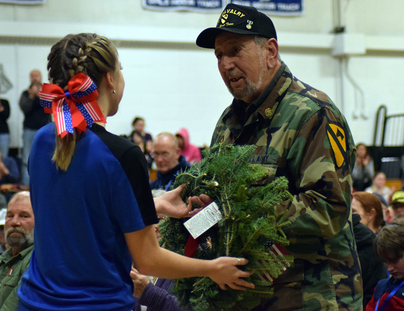 Lincoln Academy student Madison Bradbury presents a wreath to Francis Mortuori, a U.S. Army veteran of the Korean War, during the Wreaths Across America convoy stop at the Newcastle school Sunday, Dec. 8. (Evan Houk photo)