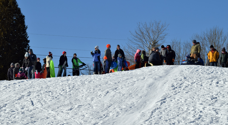 Parents, students, and staff from Bristol Consolidated School watch other sledders brave the hill at Wawenock Golf Club on family fun day, Monday, Jan. 20. The event was part of the WinterKids Winter Games. (Evan Houk photo)