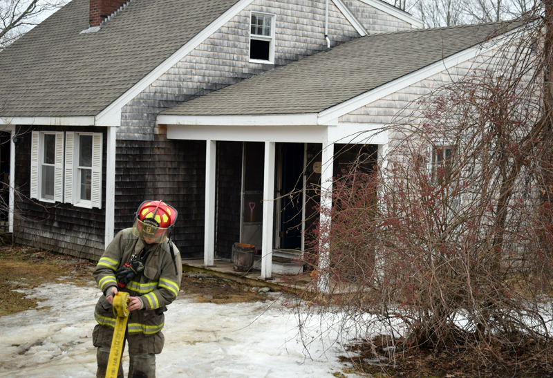 A firefighter rolls up a hose after a kitchen fire at a home in Sheepscot the afternoon of Wednesday, Feb. 26. (Evan Houk photo)