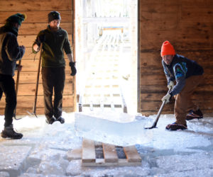 Volunteers wrangle an incoming block of ice inside the Thompson Ice House during the 2018 ice harvest. (Jessica Picard photo, LCN file)