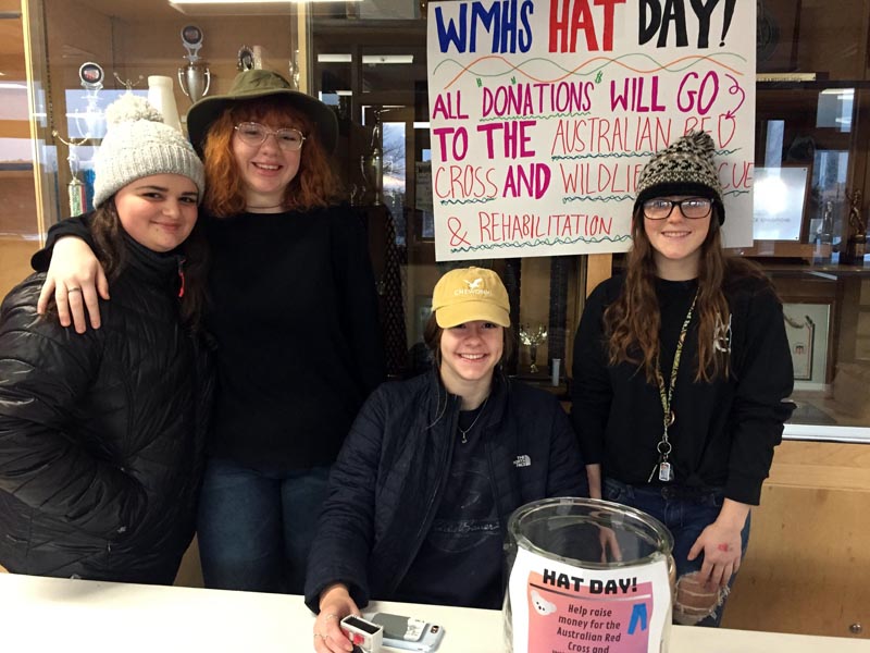 From left: Madison Westrich, Jazzy Bush, Cara Viele, and Kayla Delano staff a donation table in the lobby of Wiscasset Middle High School on hat day, Jan. 24, to raise money for victims of the Australian wildfires. (Photo courtesy Deb Pooler)