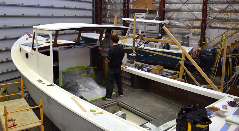 Le constructeur de bateaux principal Dylan Chase et Briland Fisher travaillent sur une nouvelle construction Holland 32 au chantier naval Gamage le 17 février. Le bateau de plaisance sera la première nouvelle construction de Gamage en près de 40 ans. (Photo d'Evan Houk)