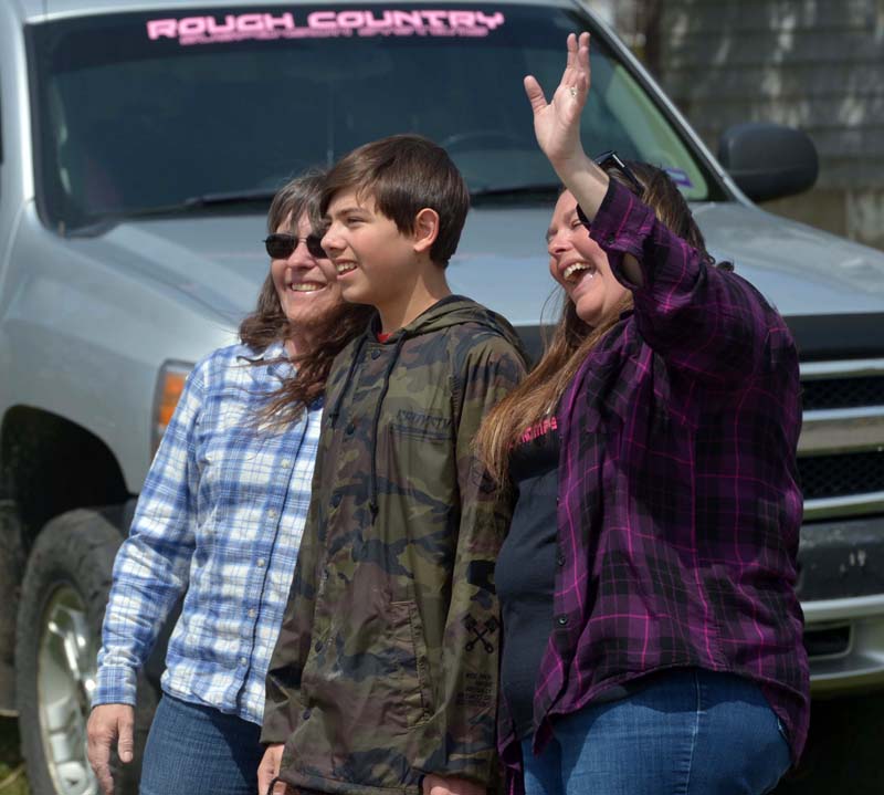 D.J. Thompson is all smiles on his 13th birthday as a parade of nearly 70 vehicles goes by his house in Jefferson to help him celebrate. He is flanked by his grandmother, Sarah Moran, left, and his mother, Laura Thompson. (Paula Roberts photo)