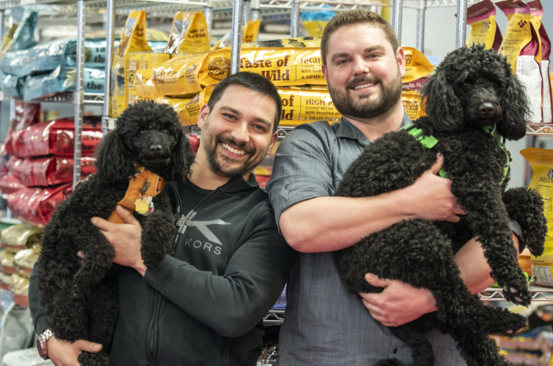 From left: Will Paul holds 4-year-old moyen poodle Zara while partner Branden Perreault holds Zara's 2-year-old sister, Kona, at The Animal House in Damariscotta on Saturday, April 25. Paul and Perreault bought the store at the beginning of April. (Bisi Cameron Yee photo)