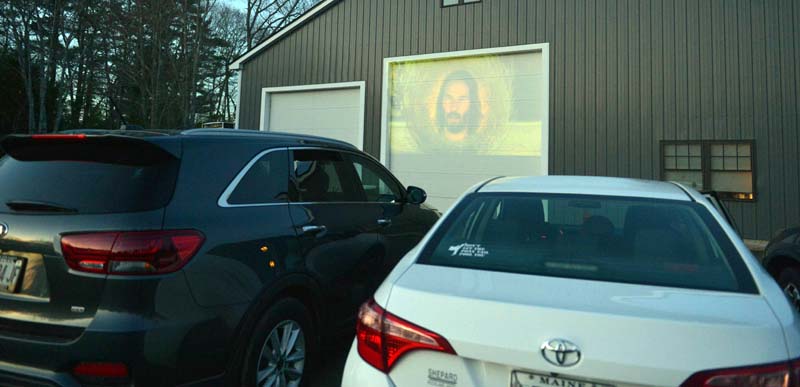 A preview of a movie plays on the garage door at Country Coach Charters in Nobleboro on Saturday night. (Paula Roberts photo)