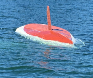 A capsized sailboat drifts in Back Cove, Waldoboro, Tuesday, May 19. The Waldoboro man on board climbed onto the bottom of the boat and held on until Friendship firefighters picked him up. (Photo courtesy U.S. Coast Guard)