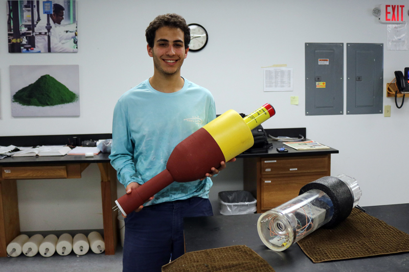 Joshua Girgis shows off a new low-cost environmental monitoring buoy he developed with a team at the Darling Marine Center in Walpole.