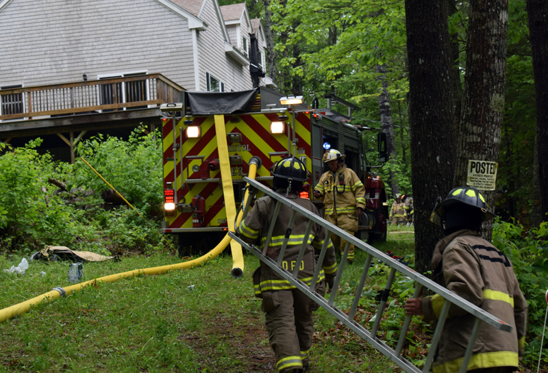 Firefighters carry a ladder to a house at 99 Atwood Lane in Bristol to assess the damage from a fire the afternoon of Saturday, June 6. A lightning strike caused the fire, which was quickly contained. (Evan Houk photo)