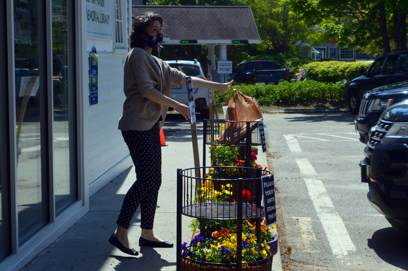 Desiree Scorcia, deputy director of community engagement and nonprofit management at the Boothbay Harbor Memorial Library, places a bundle of books in the library's parking lot for contactless pickup. (Alyce McFadden photo)