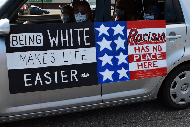 Signs on the side of a car say "Being white makes life easier" and "Racism has no place here" during a mobile protest in Wiscasset on Friday, June 5. The Artists' Rapid Response Team made the signs. (Hailey Bryant photo)