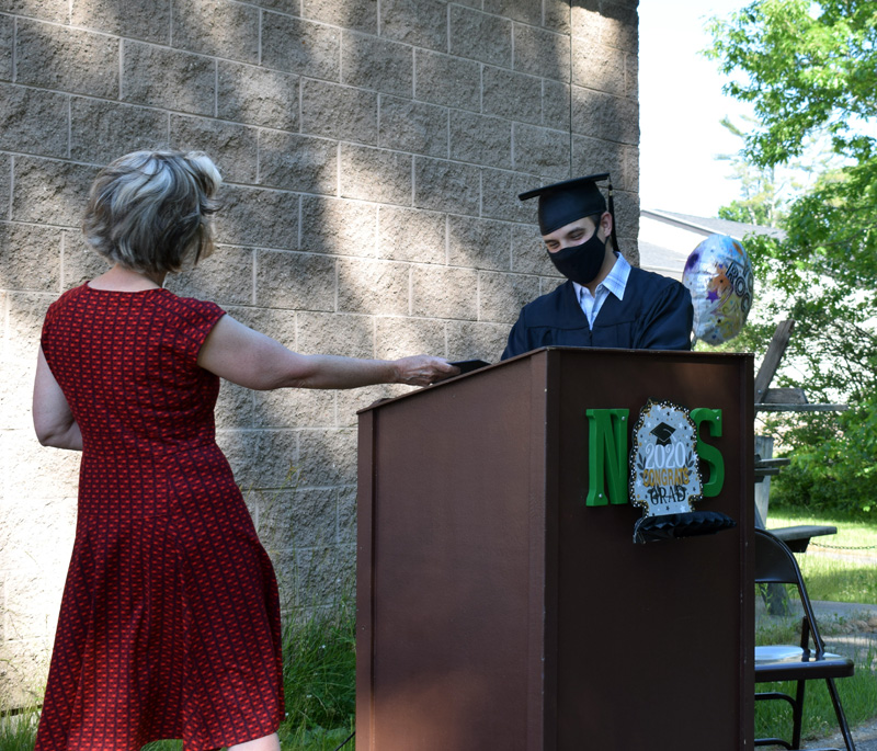 AOS 93 Director of Curriculum, Assessment, and Instruction Ann Hassett presents Central Lincoln County Adult Education's sole 2020 graduate, Brandon Rodriguez, with his diploma during a ceremony outside Nobleboro Central School on Thursday, June 18. (Evan Houk photo)