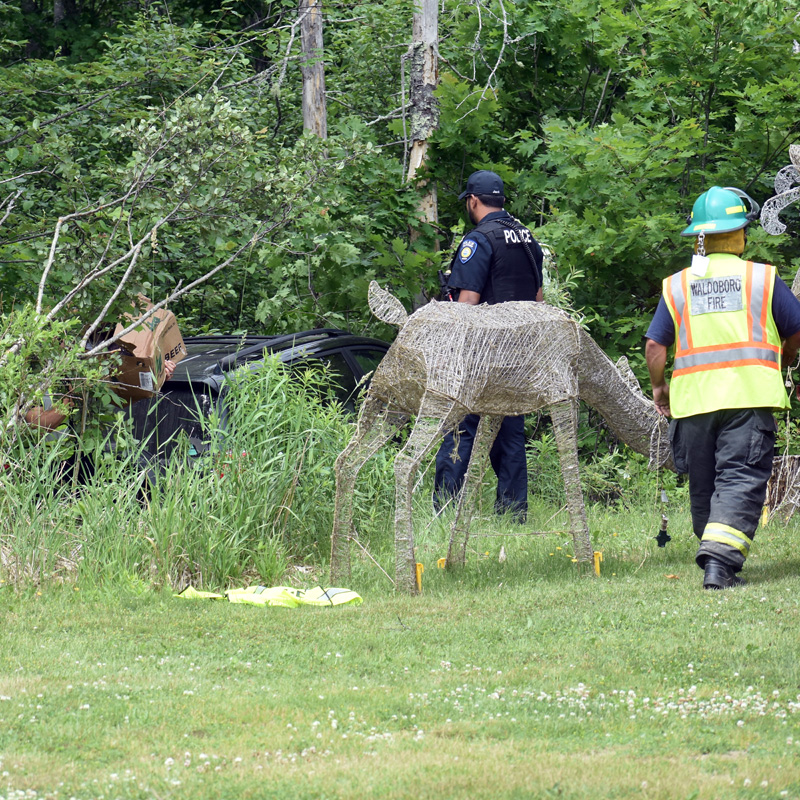 A Waldoboro police officer and firefighter help remove food from an SUV after a collision on Route 1, Tuesday, June 23. (Alexander Violo photo)