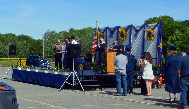 Armando Louis Cabrero III receives his diploma as soon-to-be graduates and their families wait to the side during the drive-in graduation at Medomak Valley High School in Waldoboro on Wednesday, June 10. (Alyce McFadden photo)