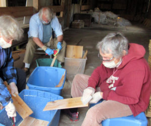 Volunteers Janice Haddock, Brad Craig, and Alexandra Jansen coat shingles with wood preservative at the Mill at Pemaquid Falls.