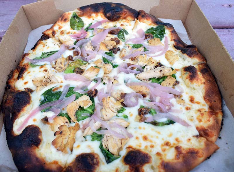 The wood-fired "Fraidy Chicken" pizza at The Village Grill Co. features chicken, Alfredo sauce, aged mozzarella cheese, red onion, roasted garlic, and spinach. (Evan Houk photo)