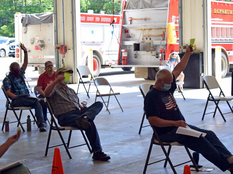 Dresden voters approve an article during annual town meeting at the fire station the morning of Saturday, July 18. The bay doors were open and chairs were set up with physical distancing in mind. (Evan Houk photo)