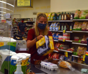 Sales Associate Irene Prescott checks out a customer at Hannaford Supermarket in Damariscotta. In April, Hannaford Bros. stores installed plexiglass barriers in checkout aisles and mandated mask-wearing for employees, among other safety precautions. (Alyce McFadden photo)