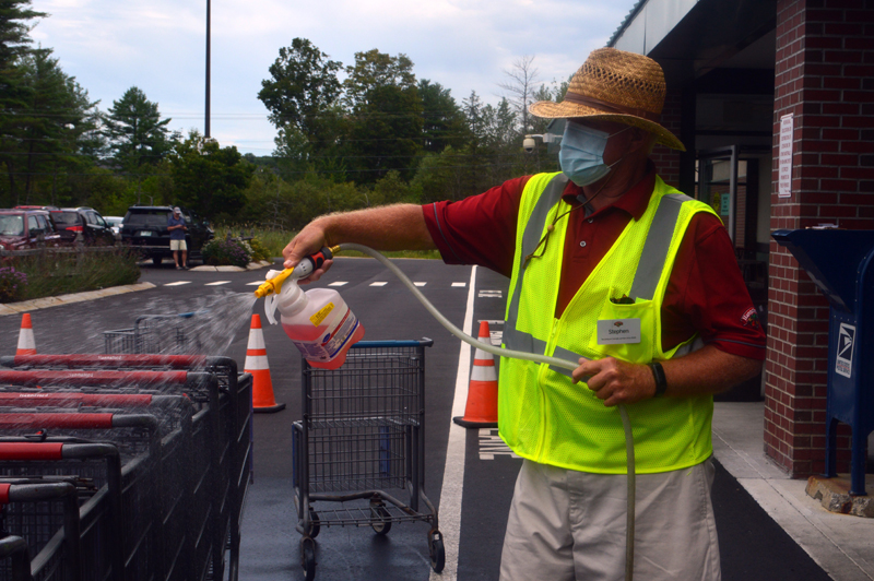 Stephen Almasi sanitizes shopping carts in the parking lot outside Hannaford Supermarket in Damariscotta. (Alyce McFadden photo)