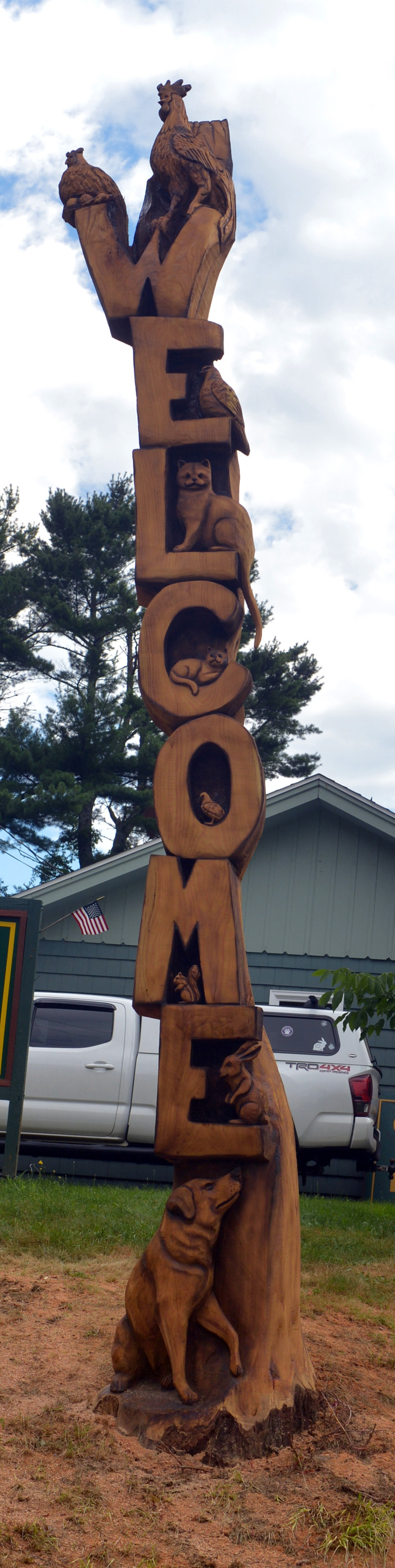 The new welcome sign at Cromwell Coastal Properties, on Route 1 in Wiscasset. When browntail moth caterpillars killed an oak tree in front of the business, owner Julie Cromwell hired Josh Landry to carve it into a sign featuring domestic animals. (Paula Roberts photo)