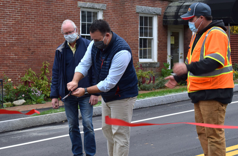 Newcastle Town Manager Jon Duke cuts the ribbon at the base of Academy Hill Road as Selectman Rob Nelson (left) and Road Commissioner Seth Hagar look on. (Evan Houk photo)
