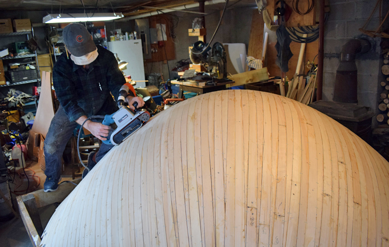 Bristol woodworker Darin Carlucci sands a wooden parabolic bowl in his home workshop on Monday, Dec. 14. A New Hampshire science center will use the bowl to demonstrate the superb hearing of owls. (Evan Houk photo)