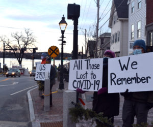 People hold signs during a drive-by COVID-19 memorial in Wiscasset on Tuesday, Jan. 19. (Hailey Bryant photo)