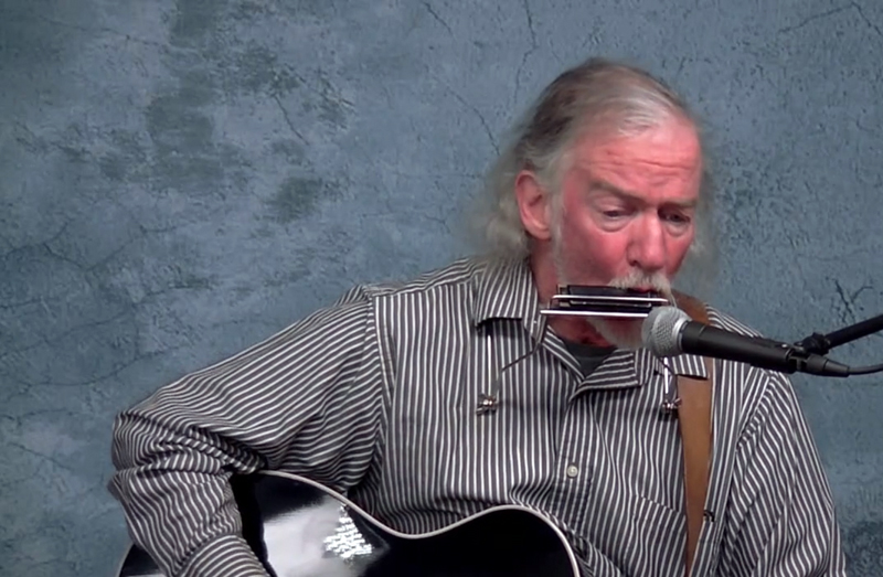 Jon Couch wails on the harmonica and plays guitar for his rendition of "Train of Glory" during Damariscotta Open Mic's Peaceful New Beginnings show, available for streaming at lctv.org. (Screenshot by Evan Houk)