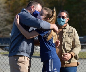 Medomak Valley High School senior Abby Lash hugs her father, MVHS Athletic Director Matt Lash, as her mother, Betsy Lash, looks on during the MVHS girls soccer team's senior recognition Oct. 9, 2020. (Paula Roberts photo, LCN file)