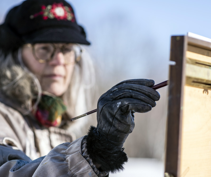 Roberta Goschke adds paint to a canvas  in Waldoboro on Sunday, Jan. 10. Her black leather gloves, supplemented by hand warmers, help her hold a brush in the cold air. (Bisi Cameron Yee photo)