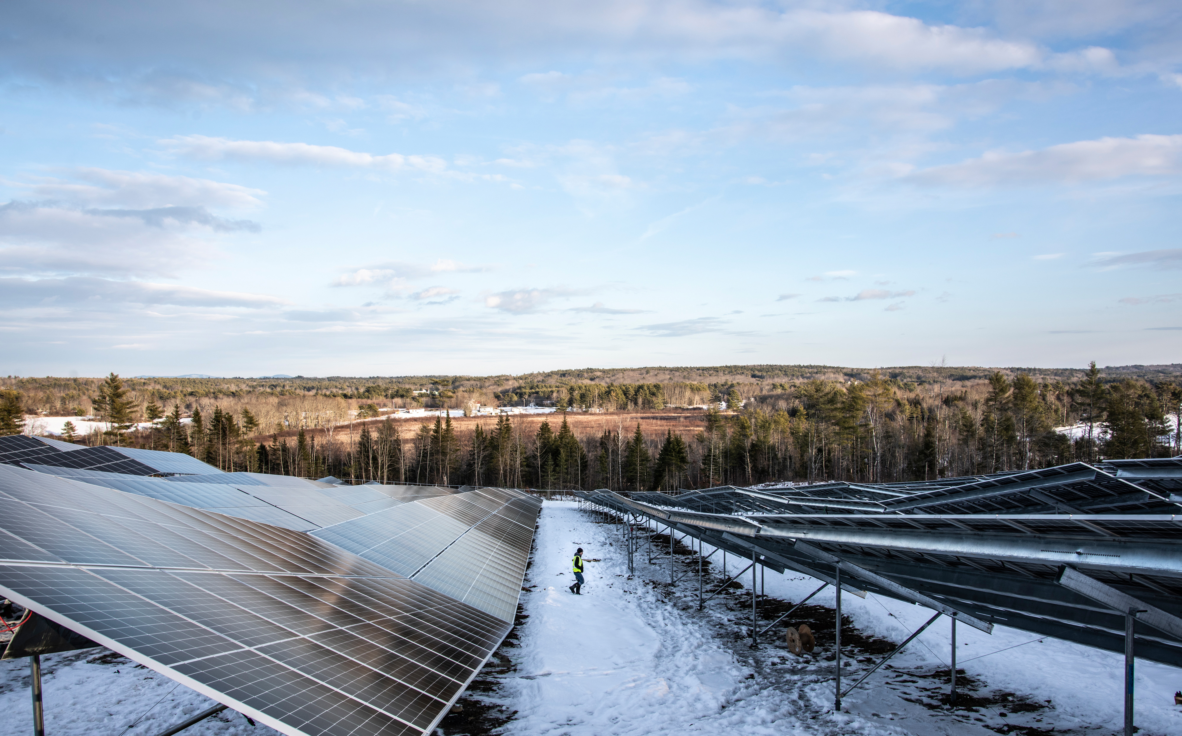 A worker walks between rows of solar panels at the SunRaise solar garden in Waldoboro on Dec. 22. About 60 people worked on the construction of the site. (Bisi Cameron Yee photo)