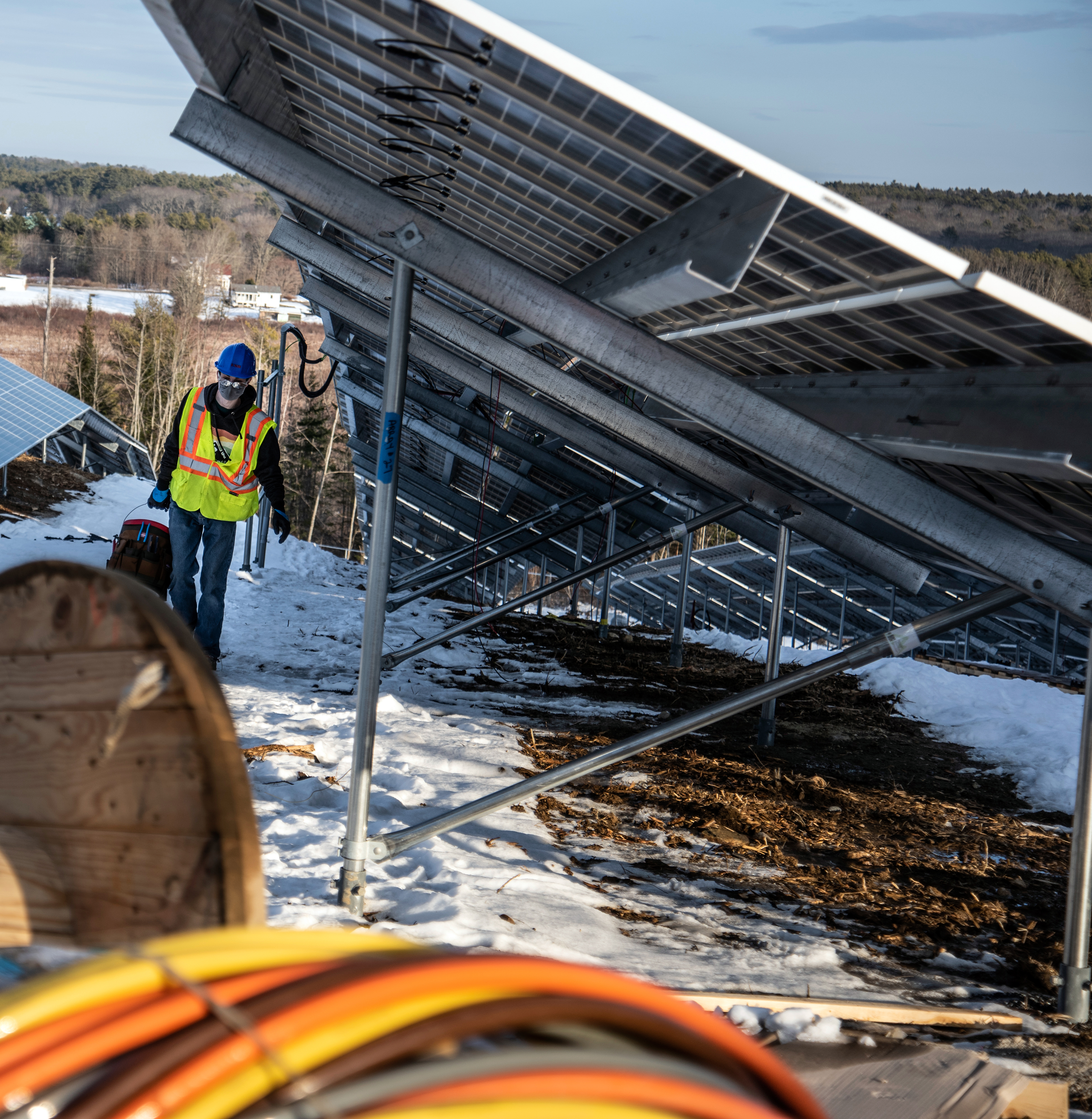A worker walks past solar panels at the SunRaise solar garden in Waldoboro on Dec. 22. The panels degrade at a rate of 0.5% a year and have 25-year warranties. (Bisi Cameron Yee photo)