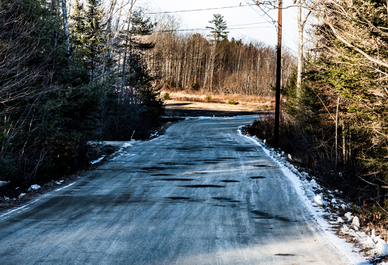 Potholes dot the gravel surface of Controversy Lane near its exit onto North Nobleboro Road in Waldoboro on Saturday, Jan. 23. (Bisi Cameron Yee photo)