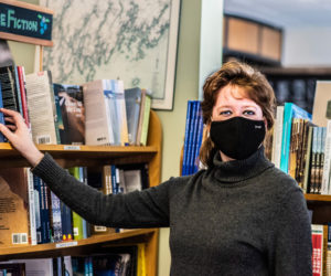 Chloe Deblois adjusts the placement of a book at Sherman's Maine Coast Book Shop in Damariscotta on Sunday, Feb. 21. Deblois has worked for the store for 12 years and managed it for the last five. (Bisi Cameron Yee photo)