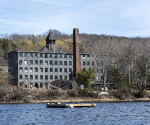 An upweller awaits deployment in the Medomak River in Waldoboro on Thursday, April 15, as the old Paragon Button Factory fills the shoreline behind it. (Bisi Cameron Yee photo)