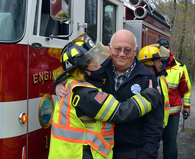 Waldoboro firefighter Marie Searles embraces Bristol Fire Chief Paul Leeman Jr. in Round Pond on Friday, April 30. Firefighters from around Lincoln County gathered to surprise Leeman and celebrate his retirement. (Maia Zewert photo)
