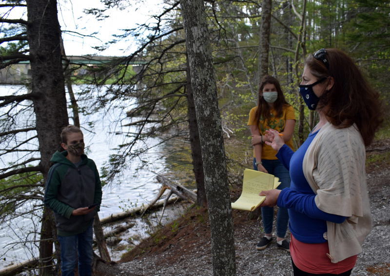 Susannah Gordon-Messer, of the Maine Mathematics and Science Alliance, speaks to Great Salt Bay Community School students Calvin Percy and Helen Duffy during a field test of the STEMports augmented reality app at the Whaleback Shell Midden State Historic Site in Damariscotta on Wednesday, May 12. (Evan Houk photo)