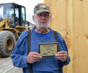 Eben Hunt holds a plaque recognizing N.C. Hunt for placing third in the Maine Association of Broadcasters' Best Campaign competition in 2019. Hunt voices the ads, but spends most of his days using the loader in the background to screen loam at the Jefferson lumberyard. (Evan Houk photo)