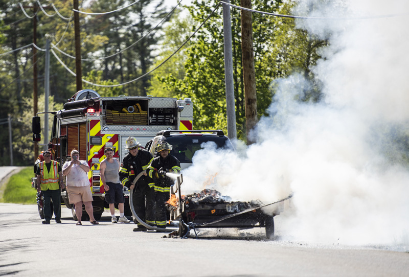 A family from Cushing watches as firefighters extinguish a fire on their utility trailer in Waldoboro on Wednesday, May 19. (Bisi Cameron Yee photo)