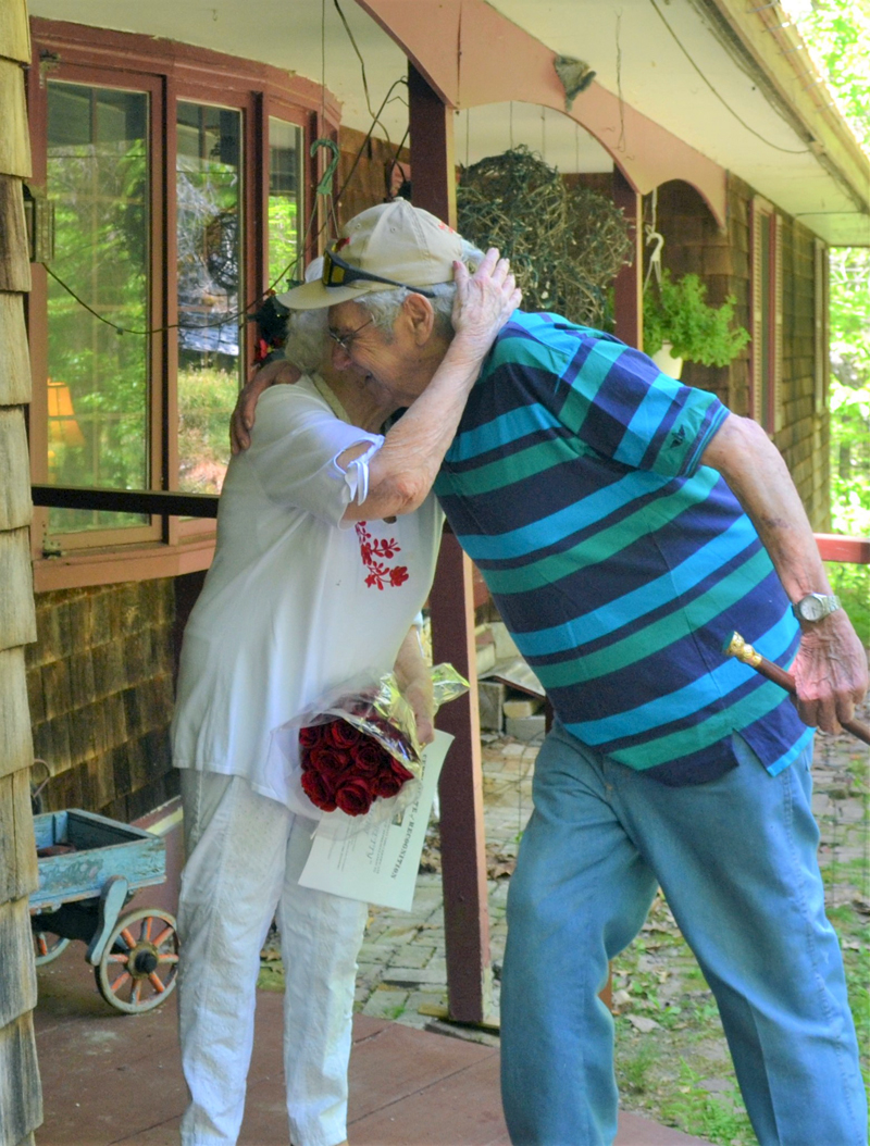 Bette Monfort gives Westport Island First Selectman George Richardson Jr. a hug at her home on the island, Friday, May 21. Richardson and Third Selectman Ross Norton presented Monfort with the town's Boston Post Cane and a dozen red roses. (Charlotte Boynton photo)