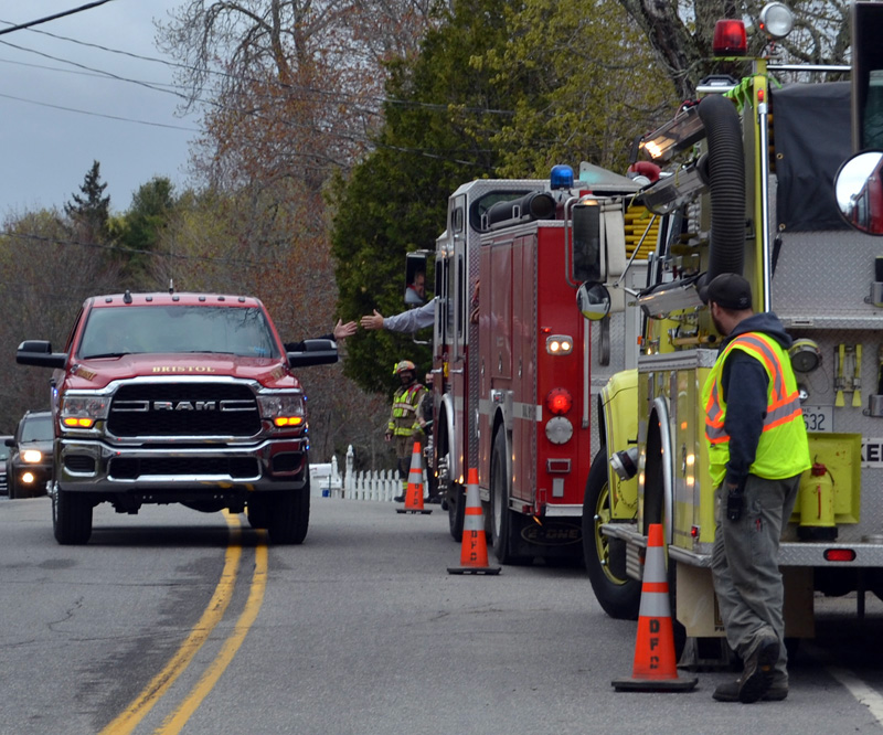 Bristol Fire Chief Paul Leeman Jr. reaches out to high-five Jefferson Fire Chief Walter Morris while driving along Route 32 in Round Pond, Friday, April 30. Firefighters from around the county organized a surprise retirement celebration for Leeman. (Maia Zewert photo)