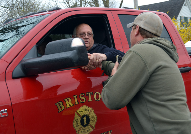 Bristol Fire Chief Paul Leeman Jr. shakes hands with Capt. Chris Hilton, of the Damariscotta Fire Department, during a surprise celebration of Leeman's retirement on Friday, April 30. Leeman was overcome with emotion as he was congratulated by a line of firefighters and other emergency workers while driving to the Round Pond station. (Maia Zewert photo)
