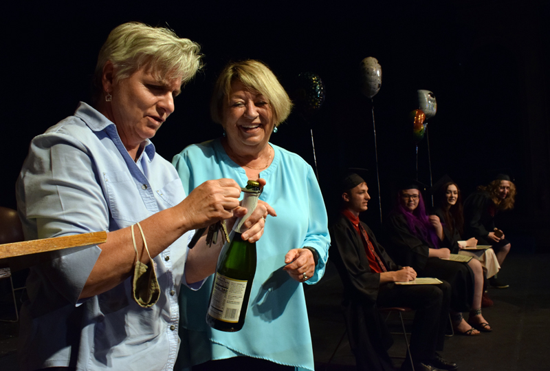 Central Lincoln County Adult Education instructor Bonnie Merrill (left) works to open a bottle of sparkling juice for a toast to the class of 2020-2021 as Director Pam Sperry and graduates look on during a graduation ceremony at the Lincoln Theater on Tuesday, June 8. (Evan Houk photo)