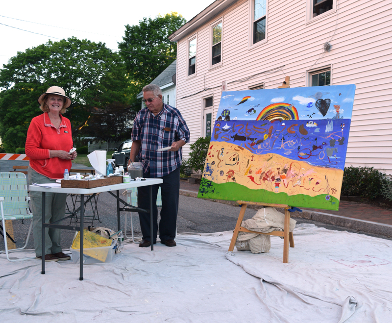 Artist Celia Ludwig (left) and her husband Stephen stand at the community mural station at the Wiscasset Art Walk on Thursday, June 24. Ludwig came up the with the idea for the mural and donated the canvas. (Nate Poole photo)