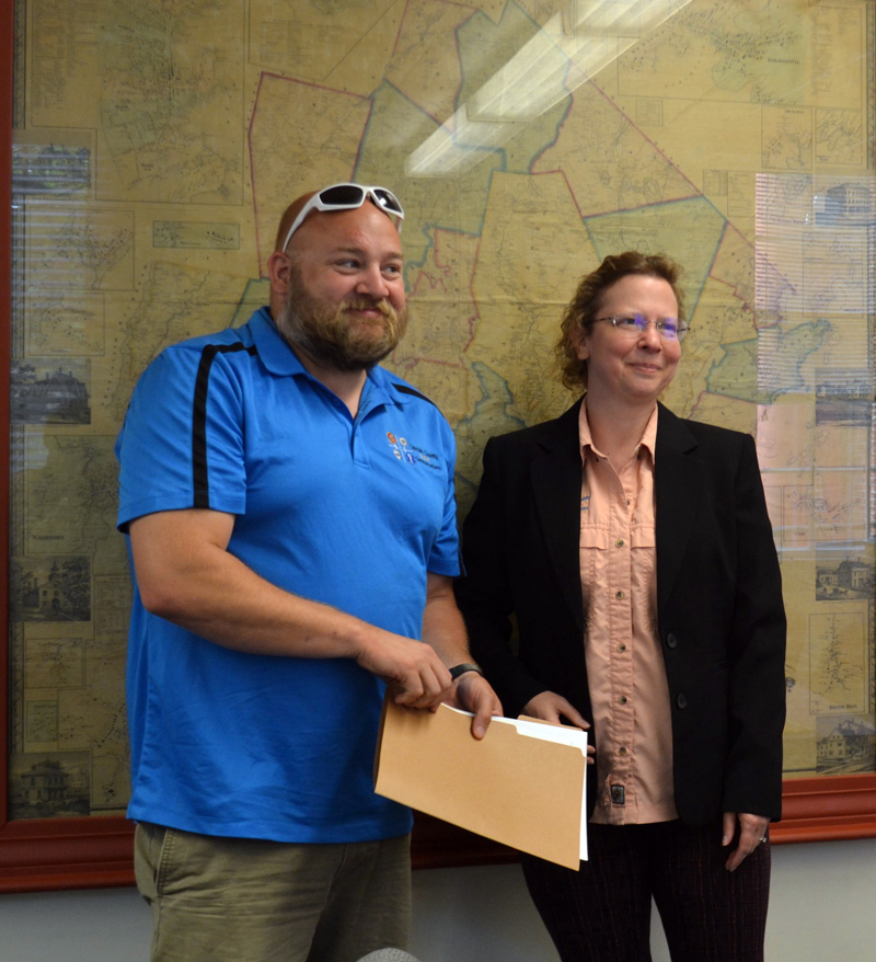 Lincoln County Communications Director Tara Doe presents the Maine EMS for Children Stork Award to Lincoln County dispatcher Josiah Winchenbach during the Lincoln County Board of Commissioners meeting on Tuesday, July 20. (Charlotte Boynton photo)