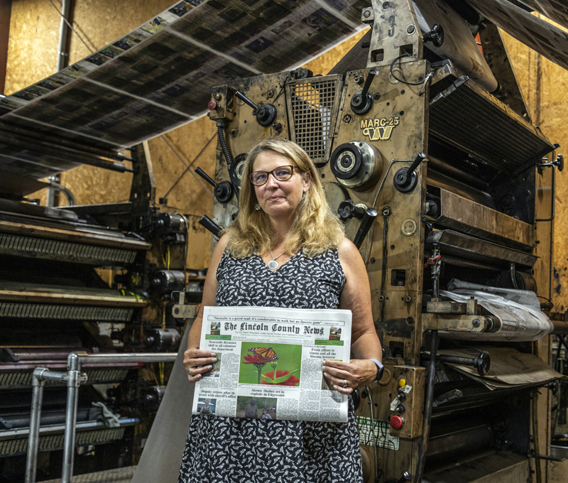 Raye S. Leonard, the new editor of The Lincoln County News, holds an edition of the paper in front of the newspaper presses at Lincoln County Publishing Co. in Newcastle. (Bisi Cameron Yee photo)