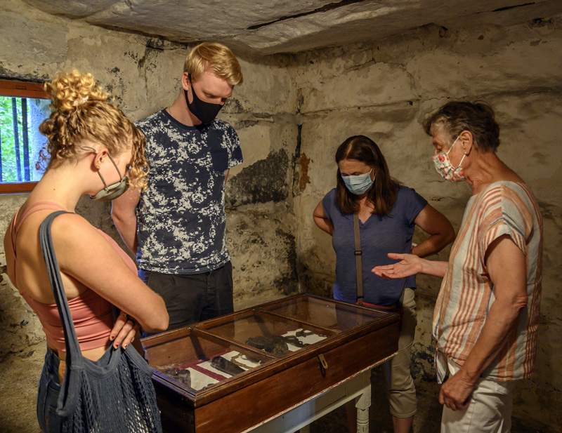 From left: Paisley Stocks, Bastian Zachariassen, Elise Paisley, and docent Christine Hopf-Lovette consider a case of handcuffs at the Old Jail in Wiscasset. Stocks and Paisley are visiting from Mill Valley, Ca., and Zachariassen hails from Denmark. (Bisi Cameron Yee photo)